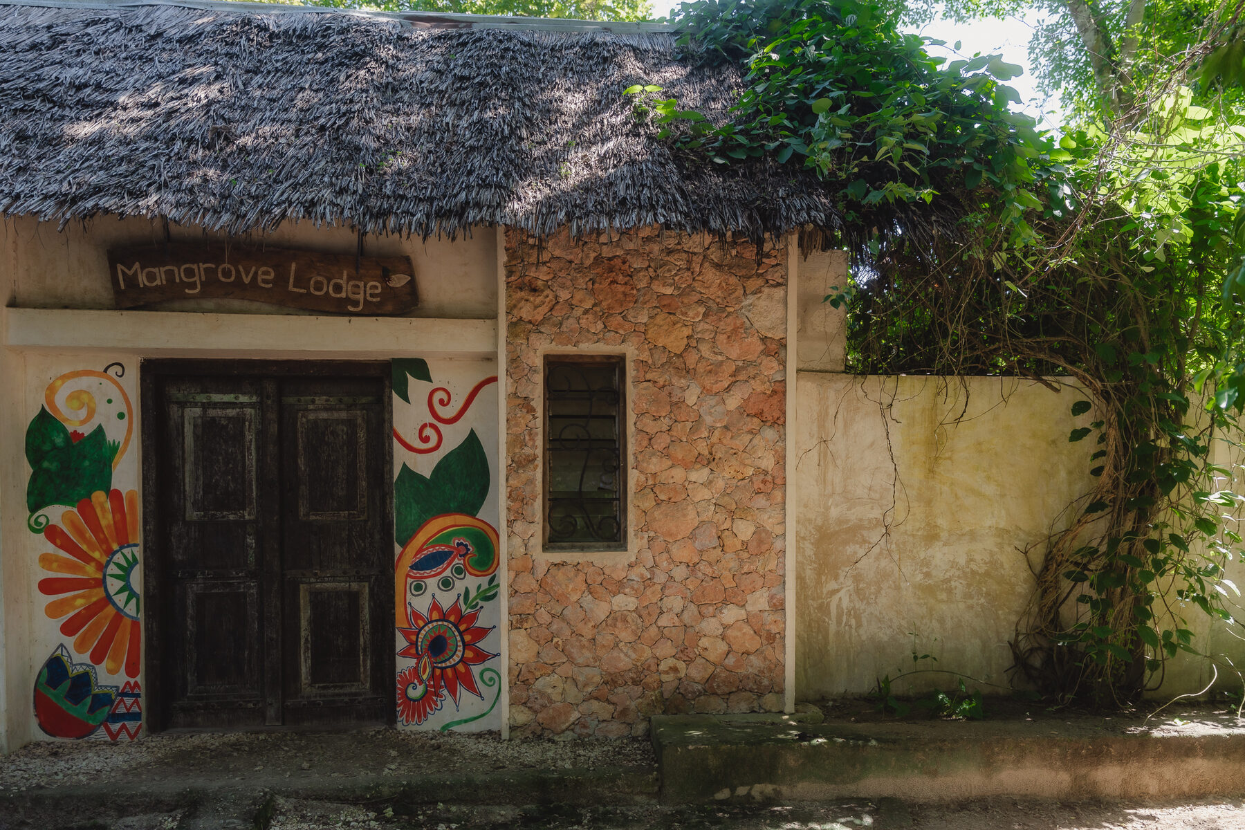 Hand-painted Mangrove Lodge entrance surrounded by greenery