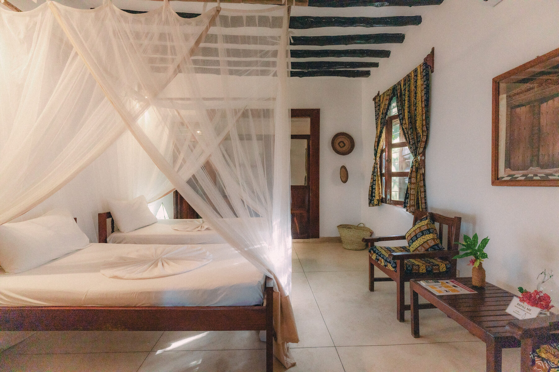 Mangrove Lodge room with a four-poster bed and colourful Zanzibari textiles